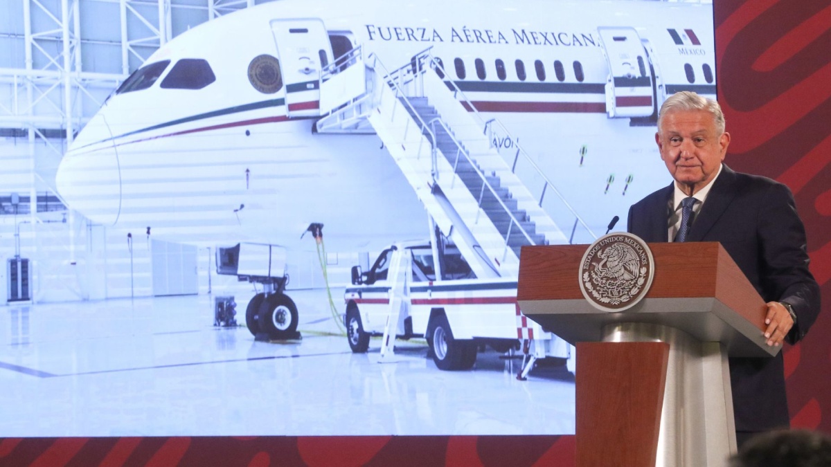 AMLO en una mañanera con el avión presidencial en la pantalla